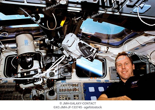 Astronaut Thomas D. Jones, payload commander, is pictured on the Space Shuttle Endeavour's flight deck with a video camera and a Linhof large format still...