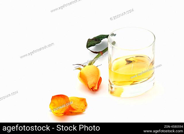 whiskey in einem glas mit einer orangen rose auf weissen hintergrund von oben