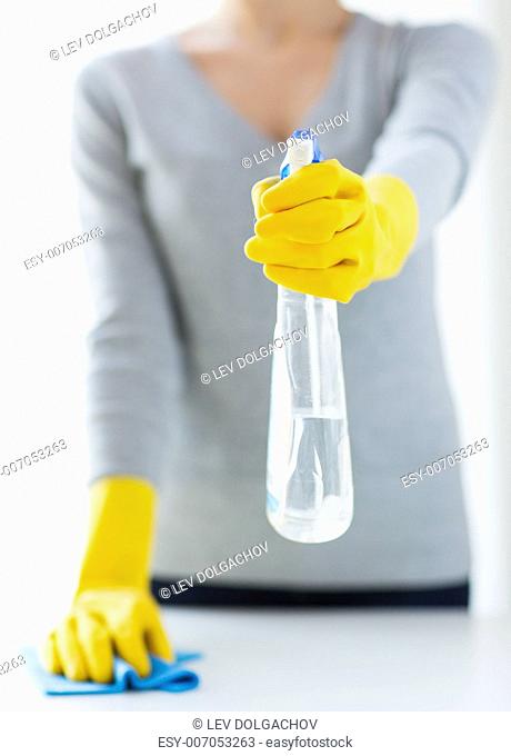 people, housework and housekeeping concept - close up of woman hands cleaning table with cloth and detergent spray at home