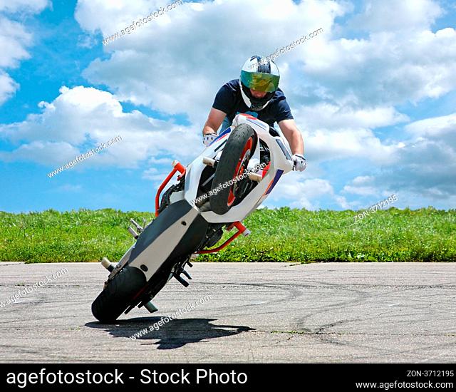 Trick on motorcycle on asphalt against sky