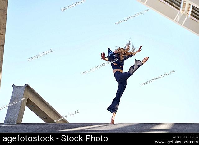 Woman with arms outstretched jumping while dancing