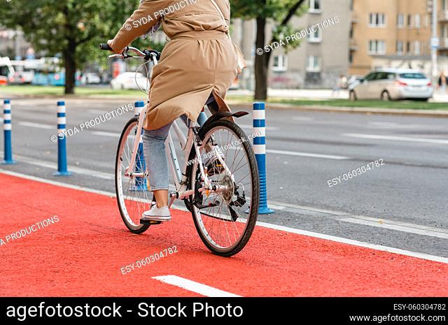 woman riding bicycle along red bike lane in city