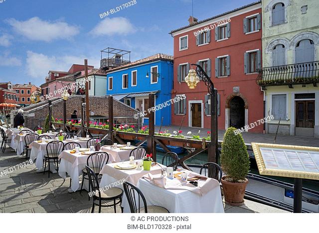 Sidewalk cafe overlooking Venice Burano canal, Veneto, Italy
