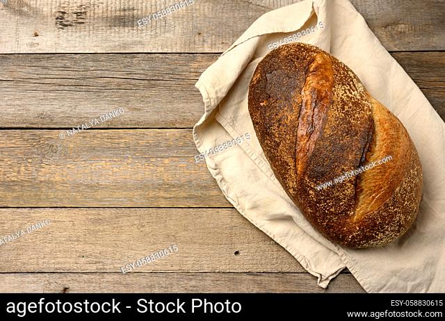 baked round bread made from white wheat board on wooden table, top view, copy space