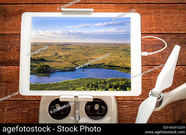 shallow and wide Dismal RIver flowing through Nebraska Sandhills, reviewing an aerial image on a digital tablet mounted on drone radio controller