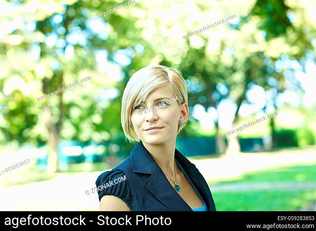 Closeup portrait of young woman in sunny park, smiling