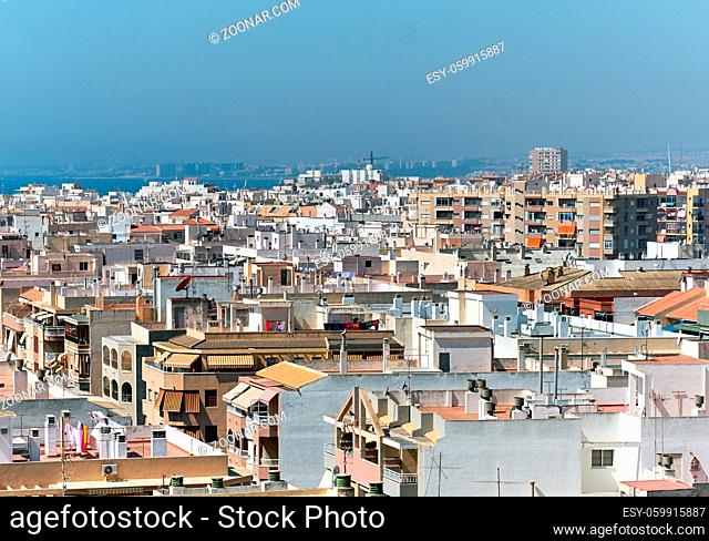 Torrevieja city in summertime. Coastal residential buildings, houses, architecture of resort town of Torrevieja. Aerial panoramic view of rooftops, urban scene