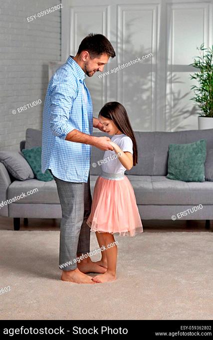 Handsome young father dancing with his little cute daughter at home. Father's Day