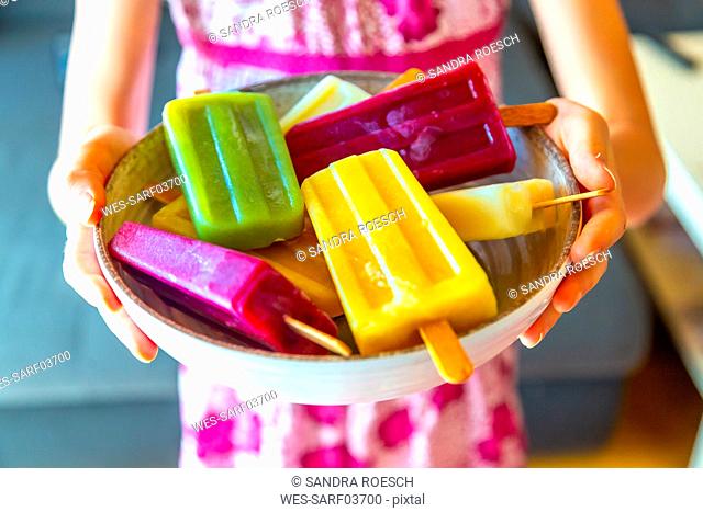 Girl holding bowl with colorful popsicles