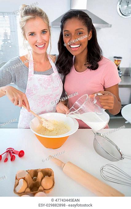 Pretty friends making pastry together looking at camera at home in kitchen