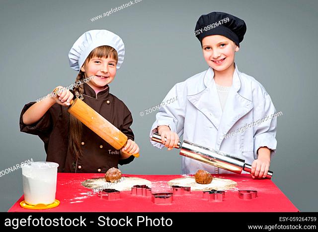 Beautiful boy and girl in chef clothes making christmas cookies with plunger over grey background. Copy space