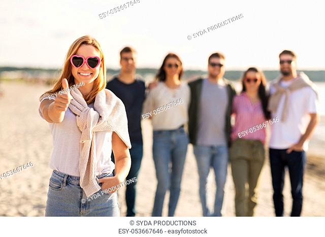 woman with friends on beach showing thumbs up