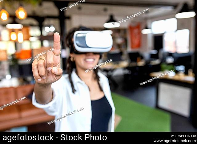 Businesswoman wearing VR glasses pointing in office