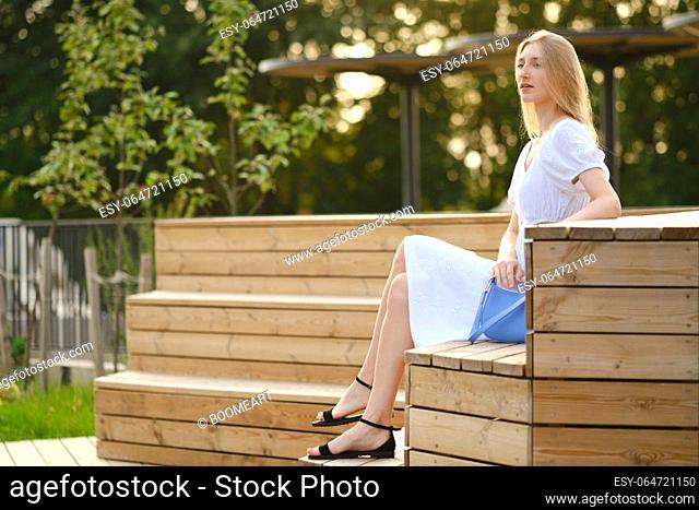 Cute woman sitting on wooden bench in profile
