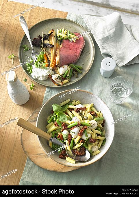 Mediterranean pasta salad and roast beef with roasted vegetables
