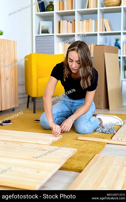 Young woman assembling piece of furniture