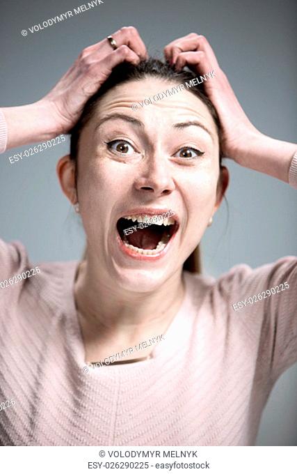 Portrait of young woman with shocked and surprised facial expressions over gray background
