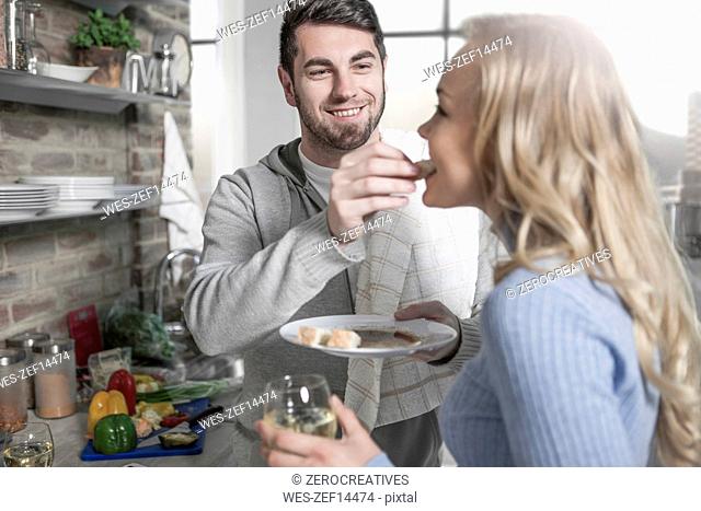 Couple tasting food together in kitchen