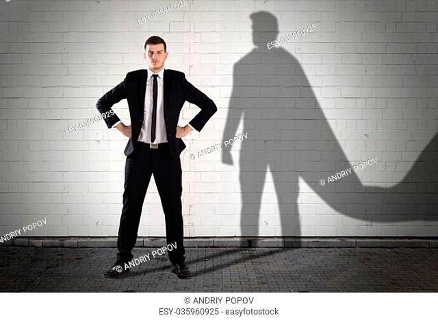 Shadow Of Superhero Formed On Wall Behind The Young Businessman
