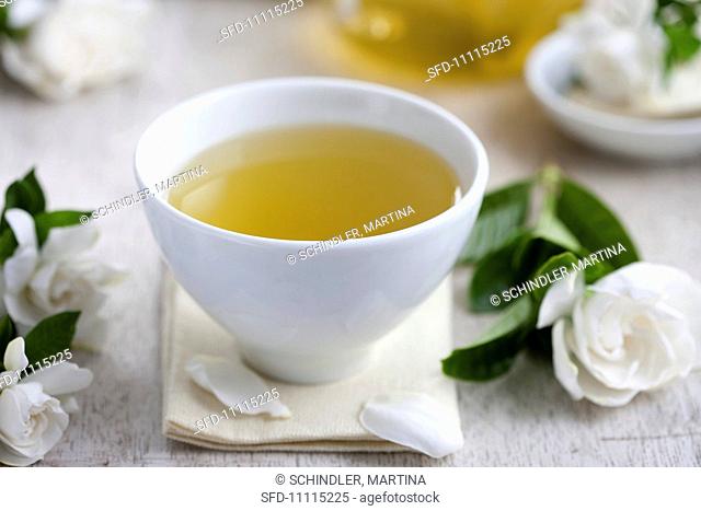 A tea bowl of green tea, surrounded by gardenia flowers