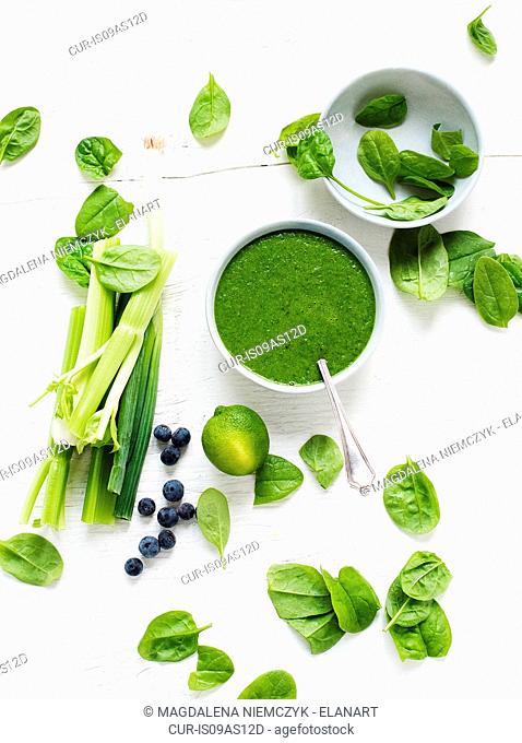 Bowl of fresh spinach soup with celery, spring onions and blueberries
