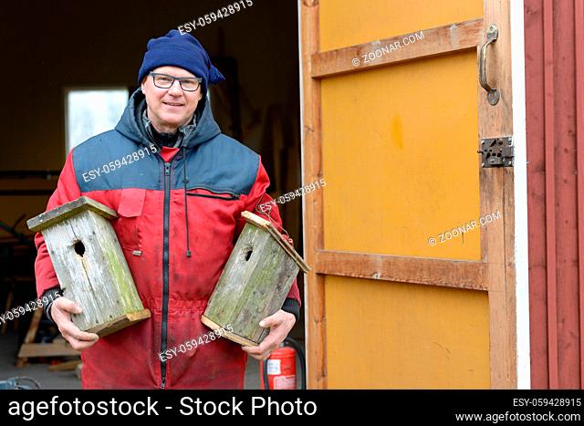Portrait of mature handsome Scandinavian man making bird house indoors