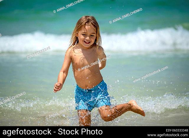 Portrait of a Cute Little Boy Running in the Water Making Splashes. Happy Child Enjoying Active Summer Holidays on the Beach Resort