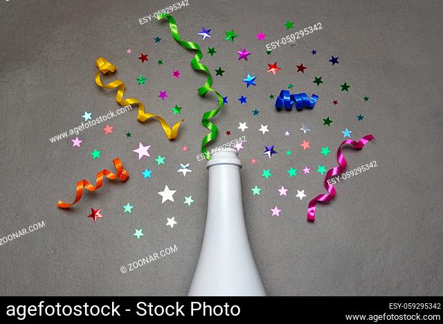 Champagne bottle on gray tile with colorful stars and ribbon