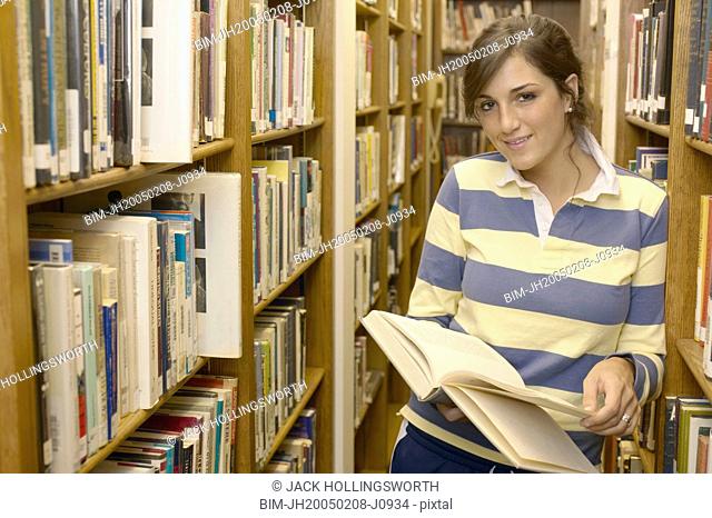 Teenage girl standing in library aisle