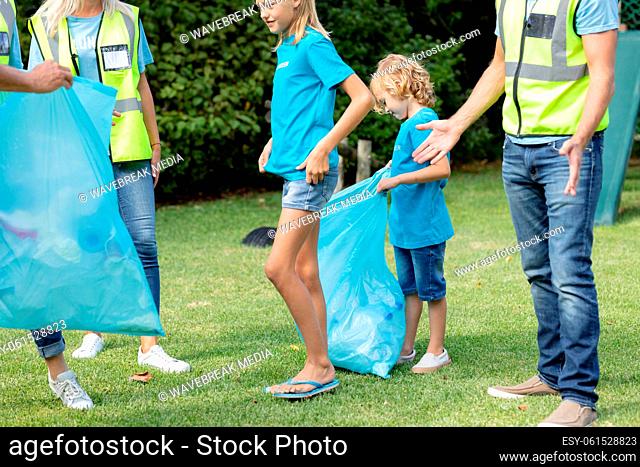 Caucasian multi generation group of men and women collecting rubbish in littered field