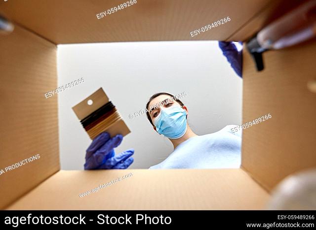 woman in mask unpacking parcel box with hair bands