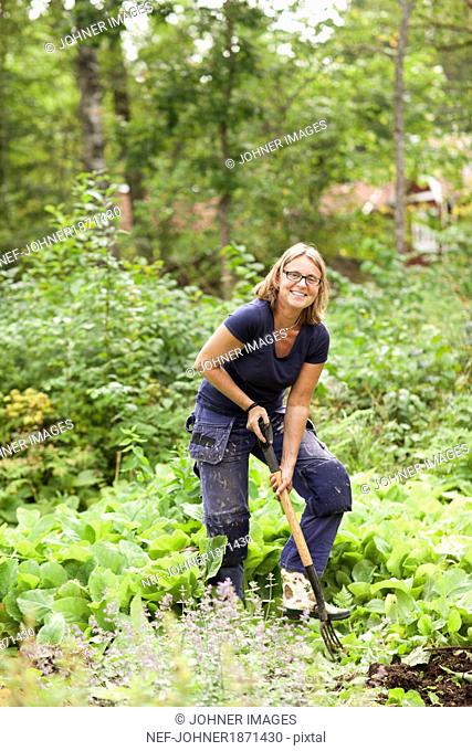 Smiling mature woman digging in garden