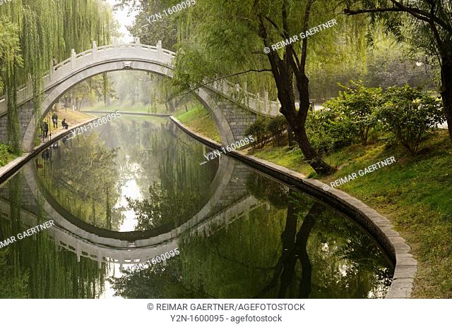Men fishing in Changhe river with stone bridge in Zizhuyuan Purple Bamboo Park Beijing