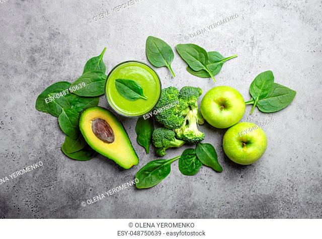 Ingredients for making green healthy smoothie, broccoli, apples, avocado, spinach over gray stone background. Clean eating, detox plan, vitamins