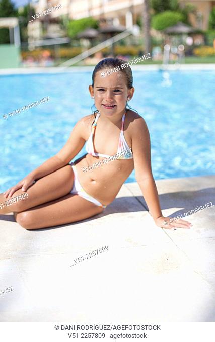 Pretty young girl in swimming pool smiling at camera