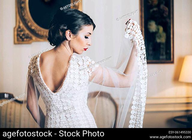 Beautiful bride posing in designer wedding dress in classical luxury interior