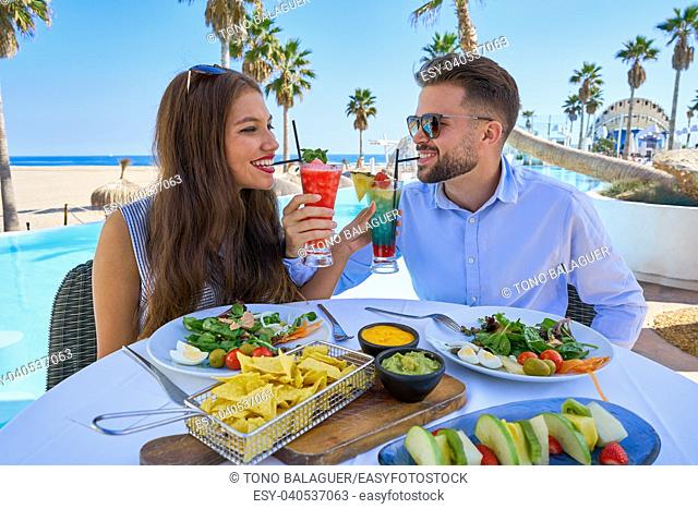 Young couple with cocktails in a swimming pool restaurant