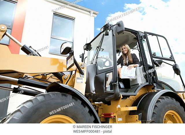 Germany, Neuss, Real estate agent driving wheeled loader on construction site