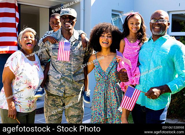 Portrait of happy multiracial army soldier with multigeneration family standing outside house