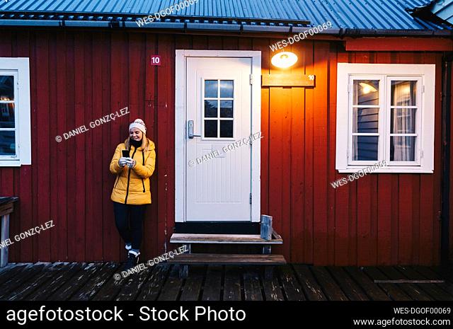 Tourist using smartphone at a hut in Hamnoy, Lofoten, Norway