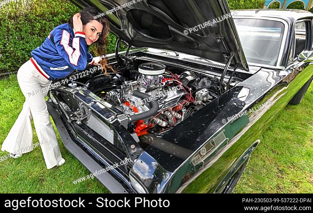 PRODUCTION - 26 April 2023, Brandenburg, Schwedt: Leokadia Hateville, airbrush and graffiti artist, stands in front of her American '69 Chevrolet Nova with a...