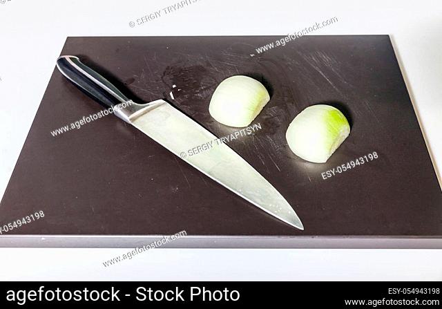 Two parts of onion and knife on the wooden board