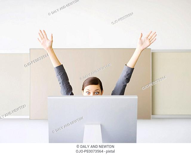 Surprised businesswoman with arms raised looking at computer