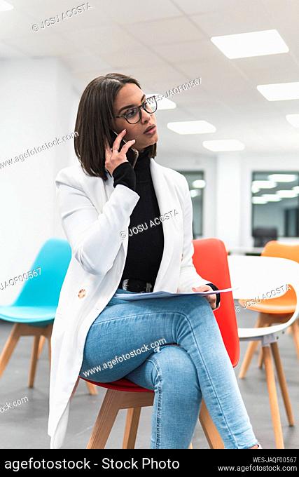 Female entrepreneur talking on mobile phone while sitting in training classroom