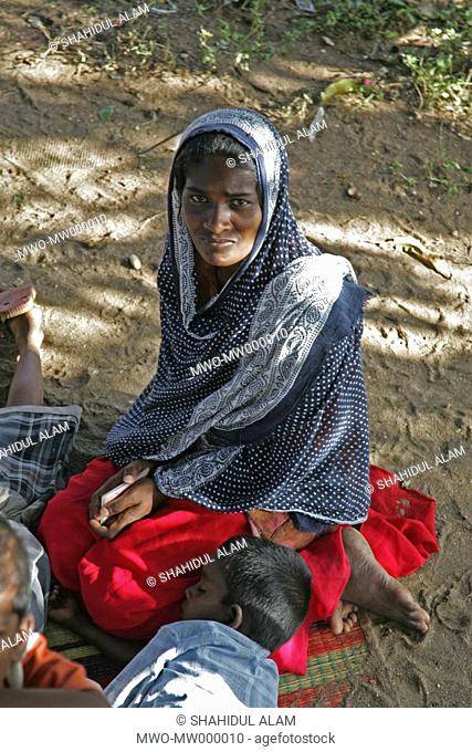 A woman and her son sitting under tree-shade in a Muslim refugee camp set up following the Indian Ocean tsunami in 2004, are waiting for relief supplies to come...
