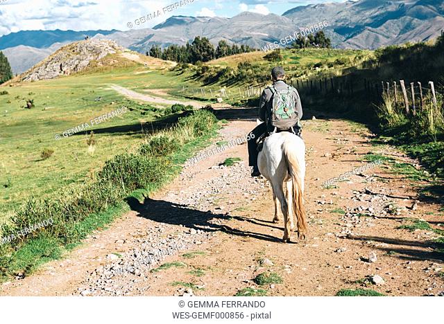 Peru, Cusco, back view of man riding horse