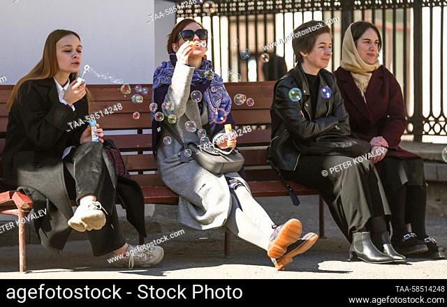 RUSSIA, ST PETERSBURG - APRIL 19, 2023: Girls blow soap bubbles sitting on a bench. Peter Kovalev/TASS