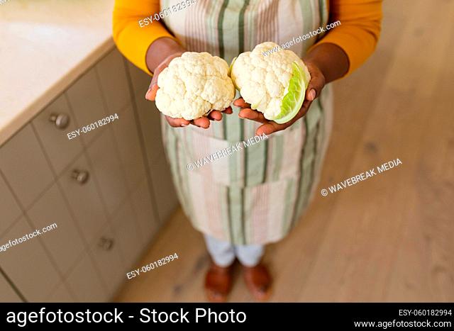 Mid section view of senior african american woman holding cauliflowers in kitchen