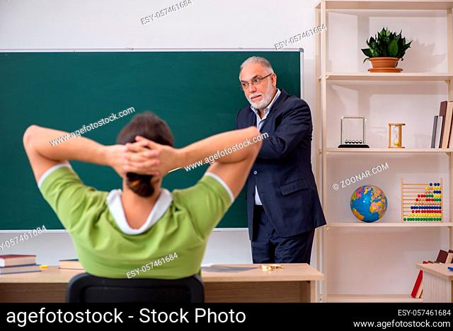 Aged male teacher and young male student in the classroom