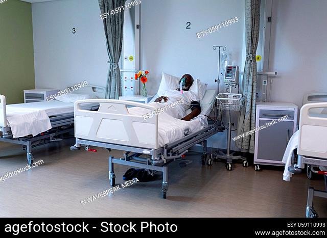 African american male patient lying on hospital bed wearing oxygen mask ventilator